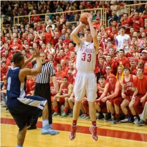 St. John's High School's TJ Kelley (#33, with ball) makes a three point shot in front of the St. John's crowd as Franklin High School's Quenten Harrell (#2, left) jumps to defend. 