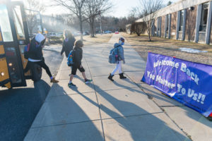 Students head into classes, passing a special sign welcoming them back after months of remote and hybrid learning. 