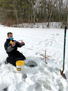MassWildlife Angler Educator Jim Lagacy measures the ice thickness at Cook’s Pond in Worcester to ensure safety during the learn to ice fish event.