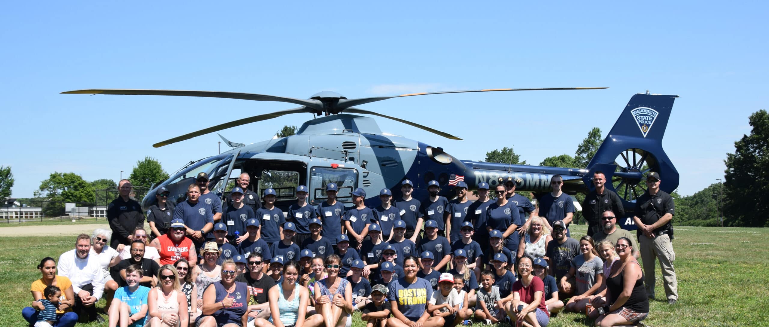 Parents, siblings, officers and cadets pose with the state police helicopter