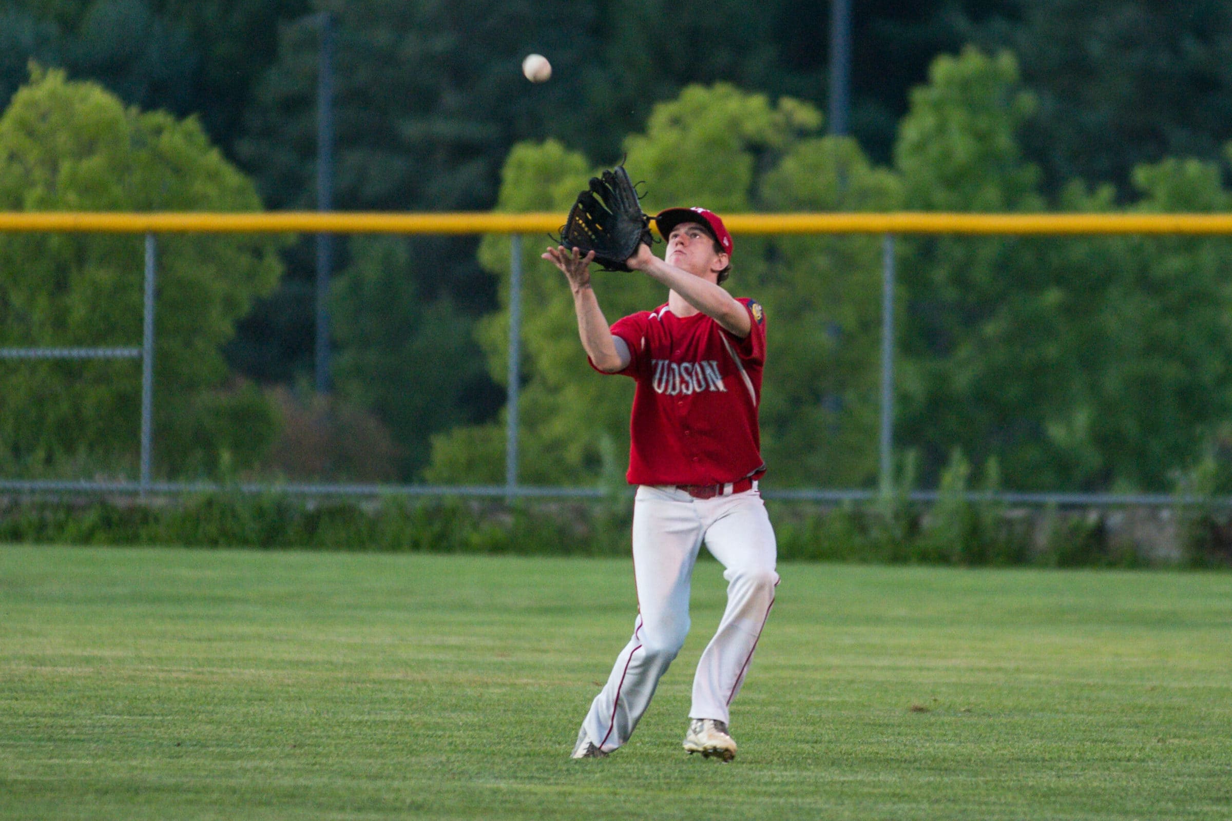 A Hudson outfielder snags a pop fly driven in his direction during his team’s July 28 game against Natick.