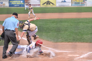 A Hamburg, New York baseball player dives towards home plate as Shrewsbury’s catcher tags him out. 