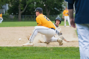 A Shrewsbury base runner slides into third base while Milford’s third baseman fields a throw from an outfielder. (Photo/Jesse Kucewicz)