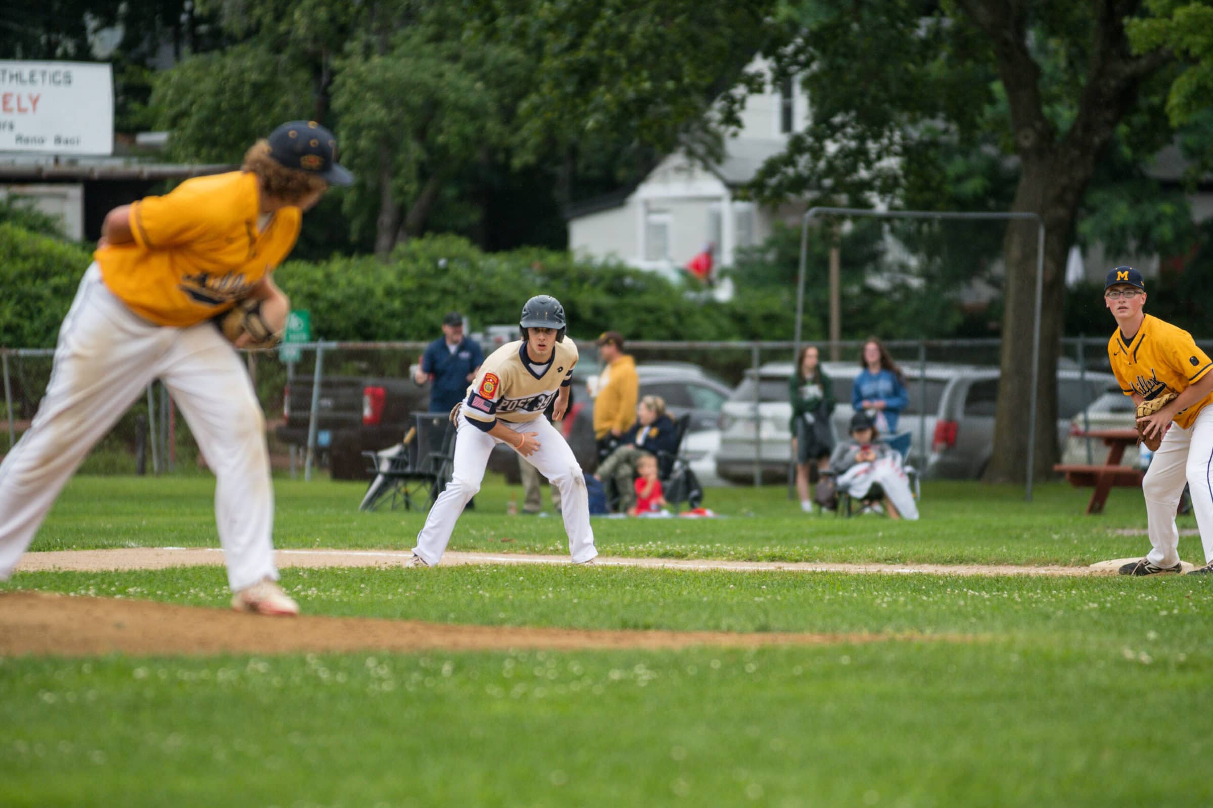 A Shrewsbury base runner looks to steal second base off while Milford’s pitcher closely watches his lead.