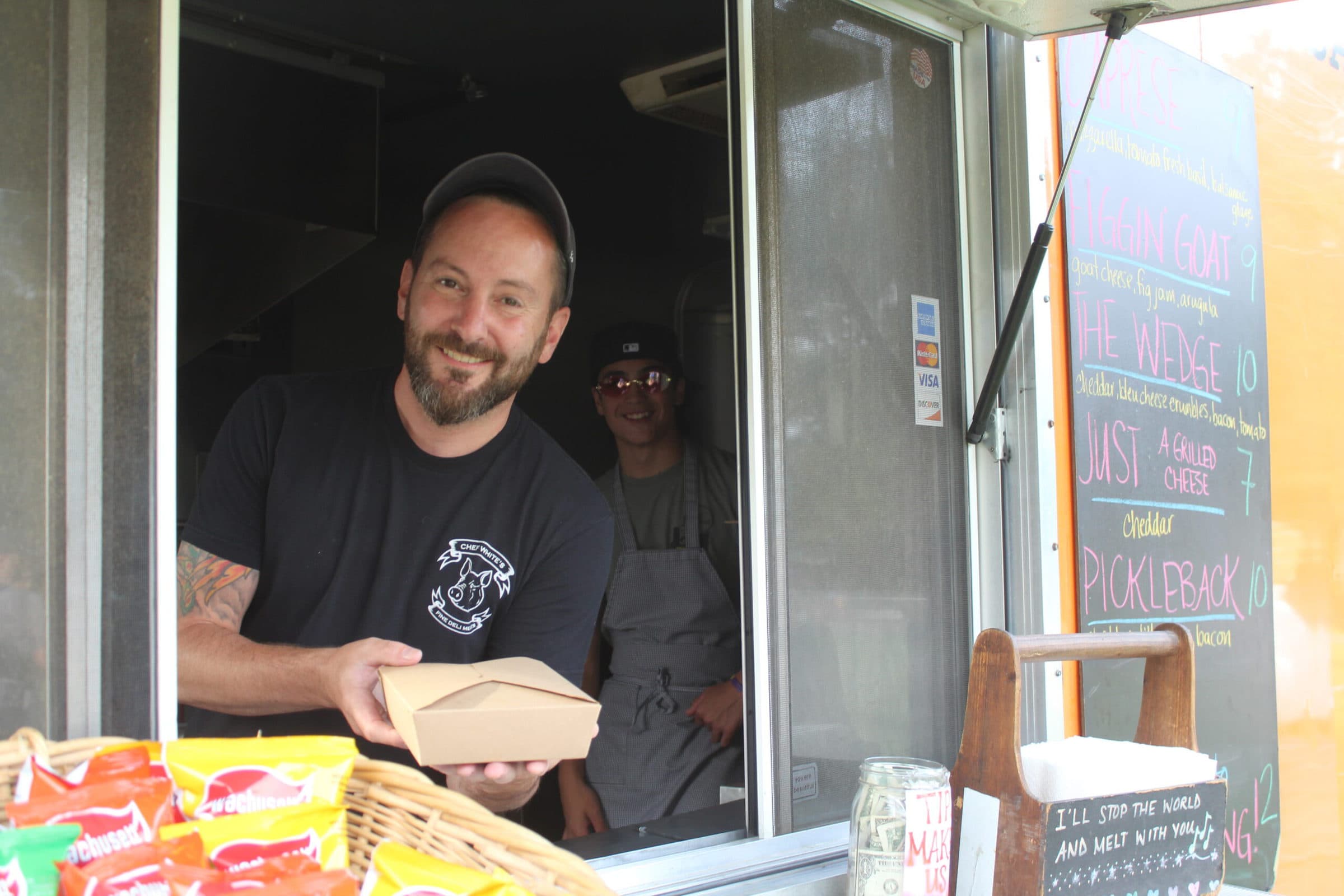 Joe, of Say Cheese! Food truck, hands a grilled cheese sandwich.