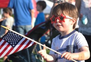 Jay Kozaczka sports his souvenir sunglasses while waving an American flag at 2019’s Westborough July 4th Block Party.
