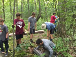Volunteers help Westborough Boy Scout Michael O’Keefe build a series of bridges over habitually muddy portions of the Libbey Trail in town. 