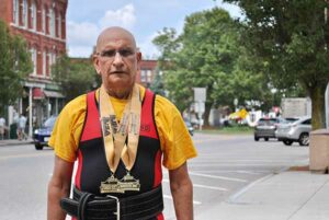Harmesh Sharma stands near downtown Westborough wearing his powerlifting medals. 