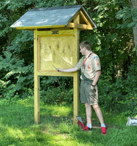 Jaxon Capobianco cuts a ceremonial ribbon across the kiosk he built at the Farley Elementary School entrance to the Danforth Falls Conservation Land.