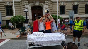 The winners of a previous Marlborough Lions Club Bed Race hold their trophy in front of the Marlborough City Hall on Main Street. The 2021 event begins along Main Street on Labor Day at 10:30 a.m.
