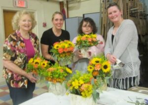 Debbie Marino, Marlowe Fayard and Kim Whitten stand with Alana Garland of The Floral Gallery in Marlborough, which recently held a centerpiece workshop for members of the Women’s Fellowship of the First Church in Marlborough, Congregational. Photo/Mary Wenzel