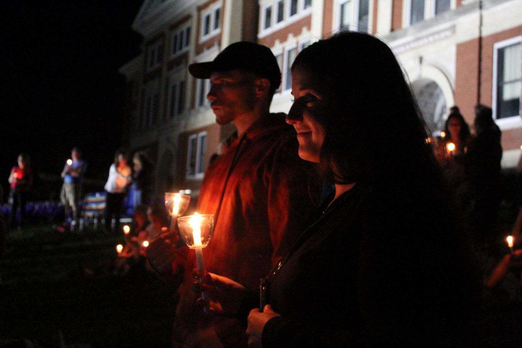 People hold candles in front of the Walker Building.