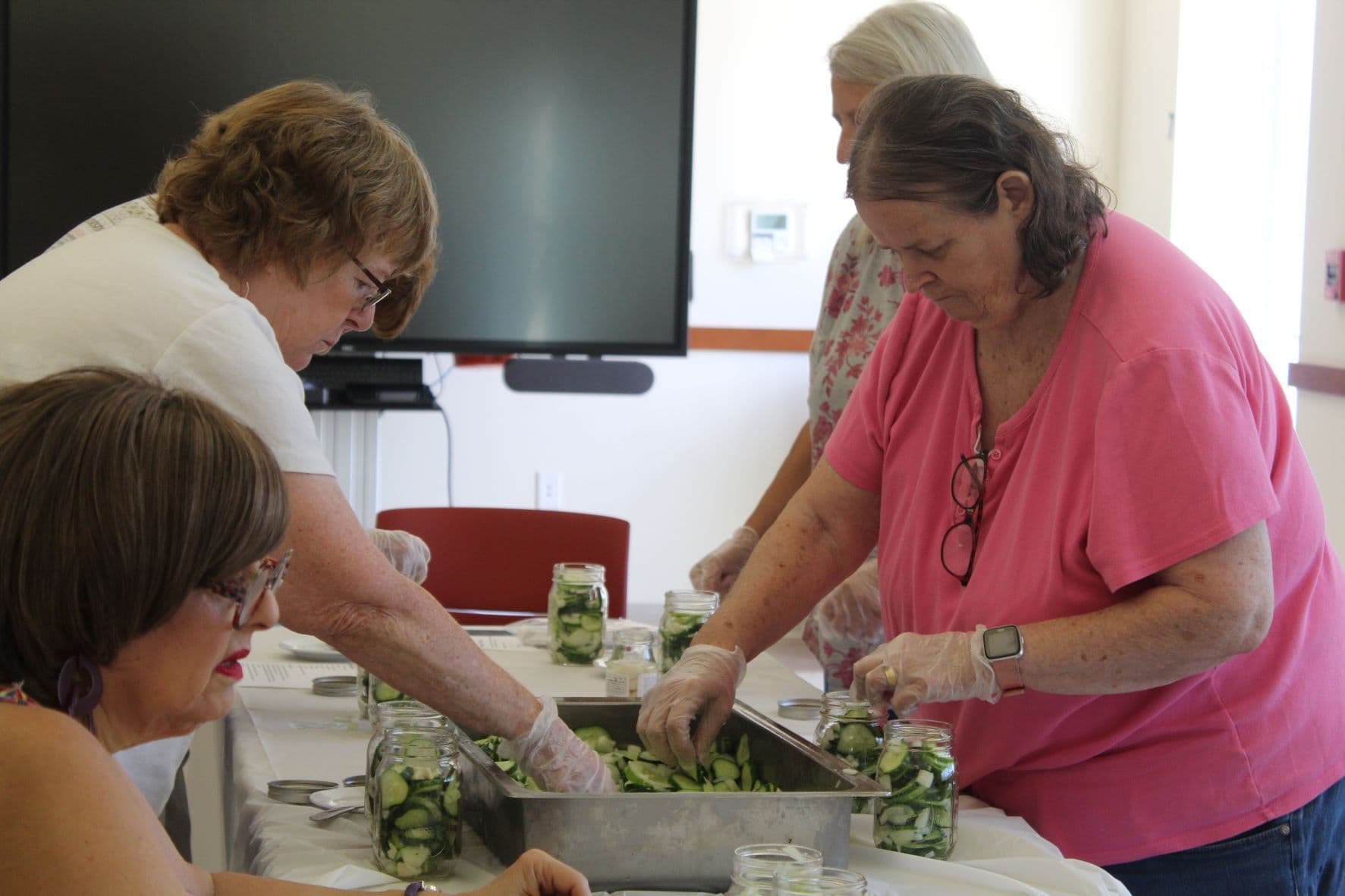 Dee Bent and Pat LeSage fill their jars while pickling.