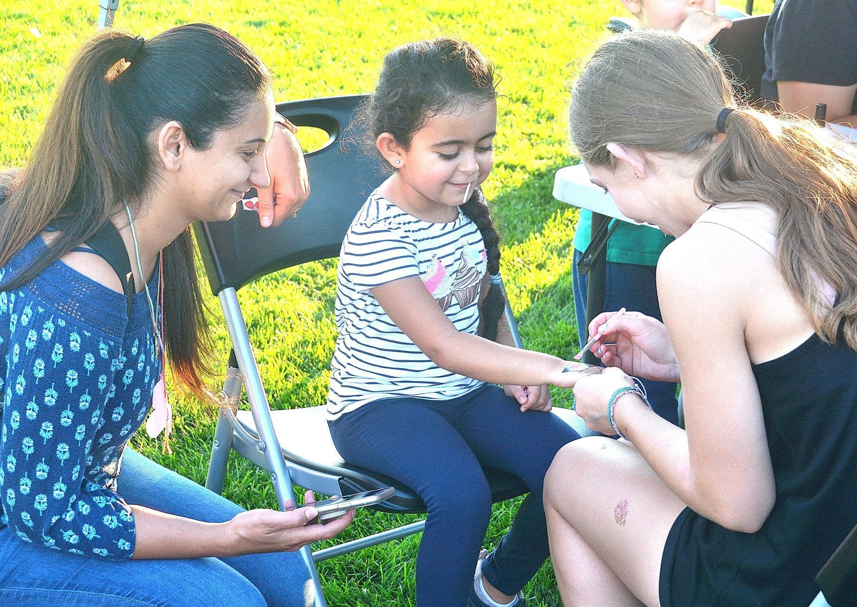 Narzwen watches her daughter Emily, 4, get a temporary glitter tattoo from a student of Diane Cournoyer Dance Center.