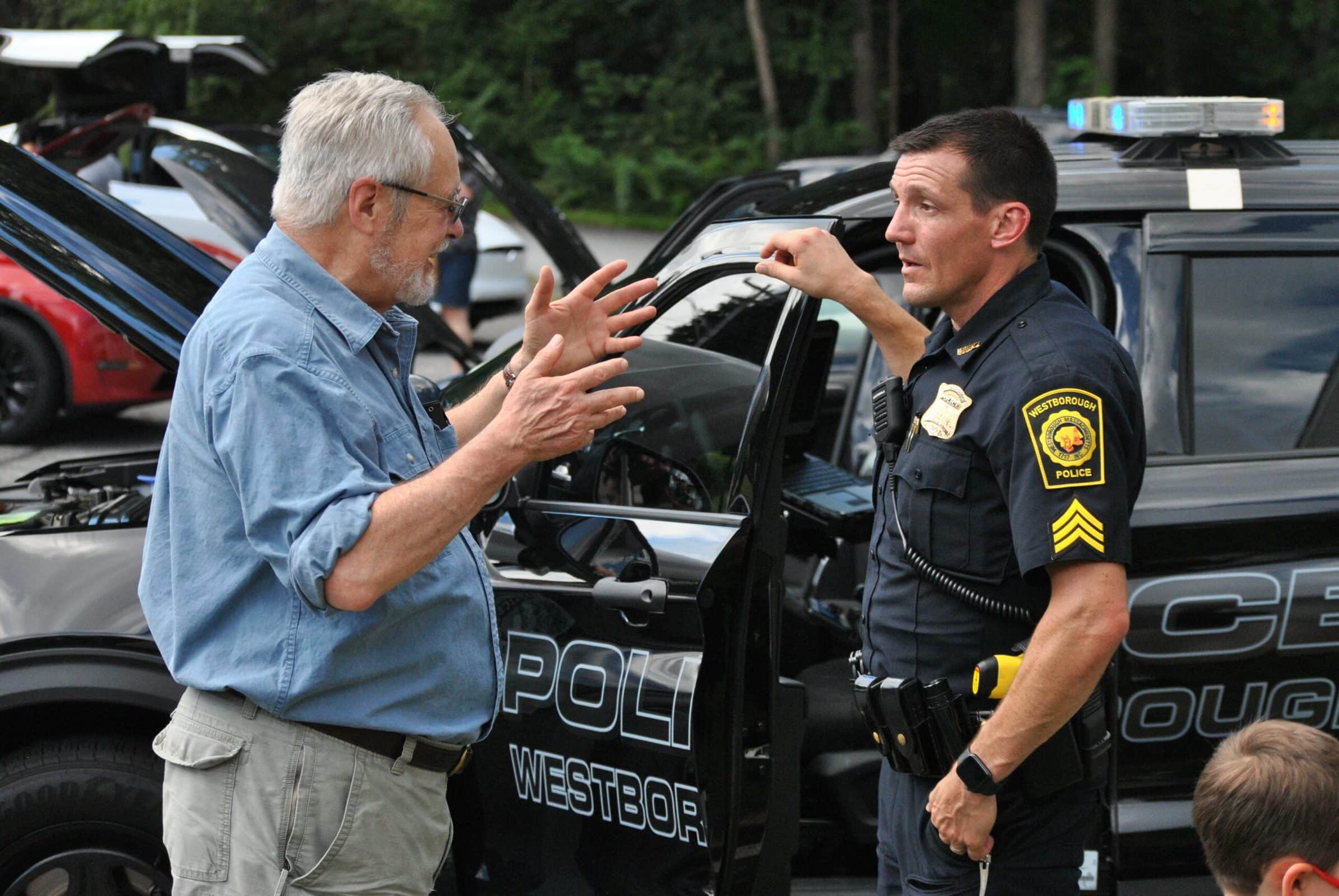 A Westborough police officer speaks with a community member next to one of his department’s hybrid cruisers during an electric vehicle informational event co-hosted by the Rotary Club and Sustainable Westborough this past summer. (Photo/Dakota Antelman)