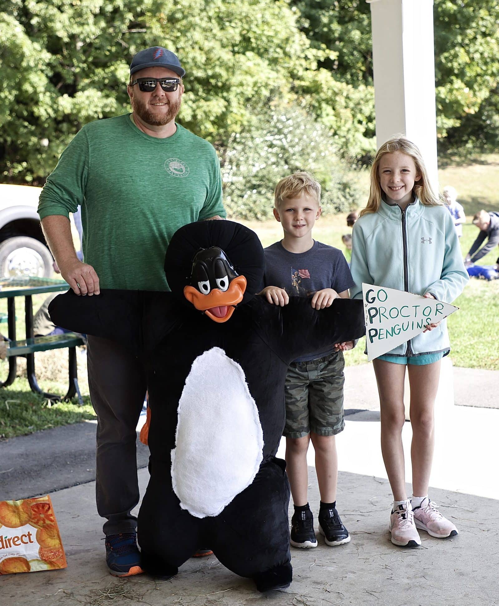 Anelin, Charlie and their dad Brian pose with a penguin-themed scarecrow.