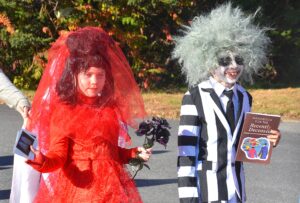 Marching in the Halloween Parade, 8-year-old friends Amelia Eaton and Cam Warden channel characters from the film and musical “Beetlejuice” while costumed as Beetlejuice and Lydia Deetz respectively. 