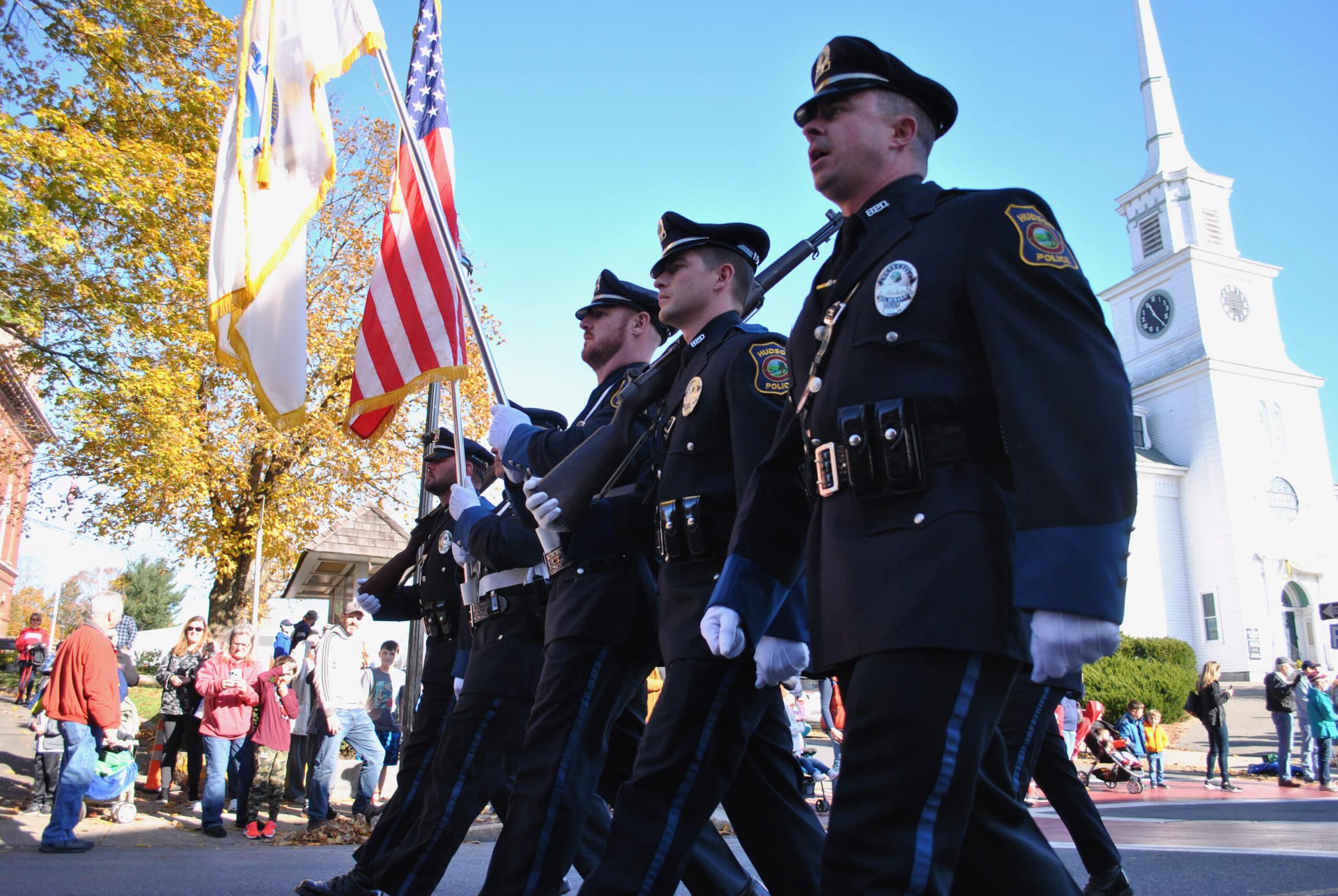 Low angle view of a police color guard marching. One is carrying a flag. Three are carrying ceremonial rifles.