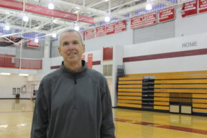 Basketball coach standing in basketball gym.