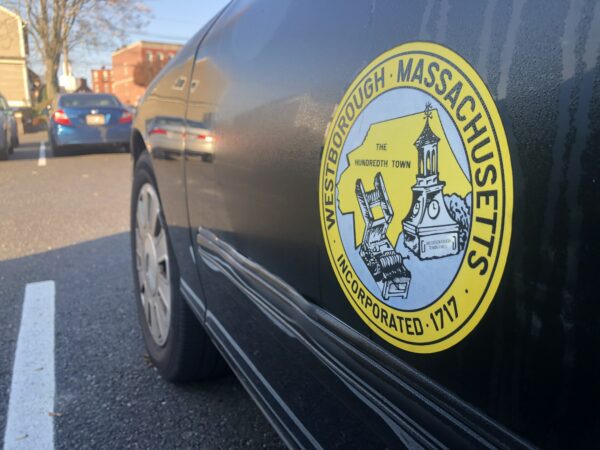 Town seal featuring cotton gin and town hall over yellow map of Westborough. "Westborough Massachusetts, established 1717" written around the perimeter of the circle.