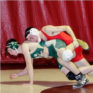 Hudson High School's Liam Haley (right, in red) takes down Nashoba Regional High School/Clinton High School's Brian Heffernan (left, in green) for two points during their match in the 170 pound weight class.