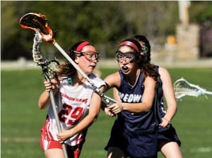 Hudson High School's Marisa Duplisea (#29, left) is blocked by the stick of Medway High School's Sarah Monaghan (#7, right).