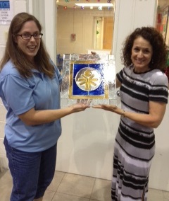 Carie Miele (left), director of GLC's Special Olympics program, presents the plaque to Marianne Frongillo, GLC president.