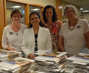 (l to r) Nancy Gilbert, Priya Rathnan, Beth Casavant and Fran Whitney pass out copies of the commemorative book that gives a history of the library from its inception in 1792 and to today.