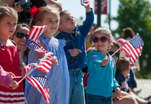 Nora Weigold, age 4, of Shrewsbury; Madeline Faucher, age 4, of Shrewsbury; and Nolan Valliere, age 5, and his sister, Adalyn Valliere, age 4, both of Millbury, are waving flags as they wait for their dads to turn the corner. Madeline, Nolan, and Adalyn's fathers are Shrewsbury police officers and Nora's father is a Shrewsbury firefighter. Katie Faucher, Madeline's mother, said that "Coming to the Memorial day parade is one of my favorite things to do every year. The kids enjoy seeing their dads march and it's a great way to learn about all the men and women who have served our country."