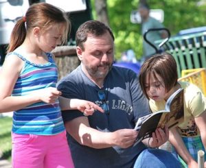 Doug Liston (center) skims his copy of “Grafton” with daughters Maya, 9, and Alex, 7.