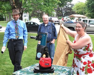 (l to r) Jim Zebrowski, president of Aldrich Astronomical Society, Inc., and John Root, coordinator of the Library Telescope Program, watch Library Director Beth Gallaway unveil a telescope given as a birthday gift. 