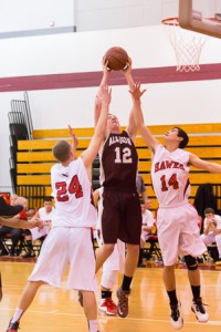 Algonquin junior Jason Truax (#12) goes up for a shot between Hudson’s Kyle Sullivan (#24) and Domenic Fontes (#14).