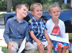 Jan and Paul Cellucci’s grandchildren (l to r) Rhys Adams, 8, Gabriel Westberg, 6, and Francesca “Frankie” Adams, 6, sit on a bench at the memorial before the dedication begins. 