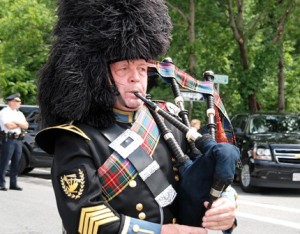Iain Massie plays bagpipes as the hearse arrives.