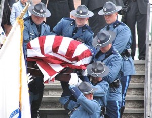 Massachusetts State Police pallbearers carry the flag-draped casket down the stairs of St. Michael Church.