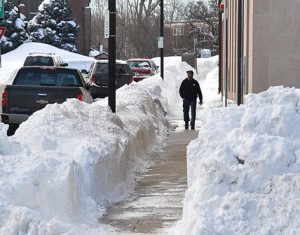 A resident walks on a snow-lined sidewalk on Main Street.