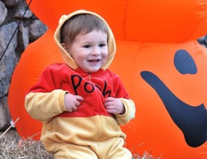 Costumed as Winnie the Pooh, Phoenix Uribe, almost 2, relaxes by a stack of jumbo pumpkins.