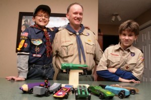 Steve Walsh, with sons Chris (left) and Johnny (right), display Pinewood Derby cars at their Hudson home. Photo/John Swinconeck 