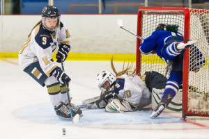 Shrewsbury’s Kylian Kelly (#10) retrieves the puck as Leominster’s Katie Babineau (#13) flies into the net after her shot is blocked by goalie Delia O’Connor Photo/Jeff Slovin 