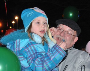 Faith Merrill, 4, gets a candy cane from Santa and a lift from her grandfather, Peter Juaire.
