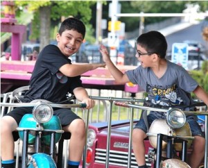Yonathan Kimyagaron, 7, and his brother Daniel, 5, give each other a high five while riding motorcycles.