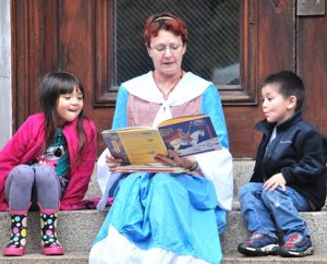Seated on the steps of City Hall, Debby Foley of the Marlborough Historical Society reads a story to Cloe Zinzola, 6, and her brother, Lincoln, 4.