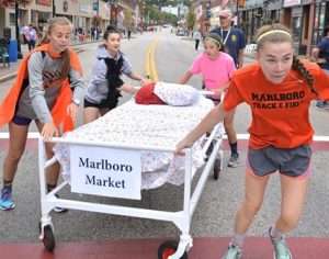 The team sponsored by Marlboro Market – consisting of Marlborough High girls cross country runners (l to r) Madison Hediger, Barbara Battisa, Christiana Kearnes and Olivia Rainville – complete applying bed linen midway on the route then continue the course.