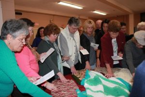 Attendees at the reception prayed over the completed shawls before donation. 