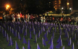 Those attending the candlelight vigil say the Serenity Prayer next to the field of flags. 