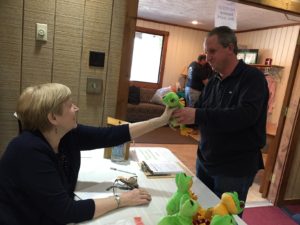 Marlea Dutt gives a stuffed animal frog to a shopper for his grandson. Several dozen donated stuffed animal frogs were given for a child or grandchild to shoppers at the free clothing giveaway. Photo/submitted