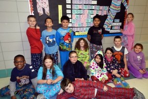 (Standing, from left) Patrick Hobin, Marco Pena, Eddie Rivera, Cleymer Agreda, Jessica Tollard, (sitting) Curtis Michel, Emily MacKay, Derek Johnson, Laysa Mesquita, Kayla Parsons, Austin Hunt, Maria Luiza Barreto, and (reclined) Seamus Heath sport their pajama party wear Dec. 11 by the pajama project's bulletin board. (Photo/submitted)