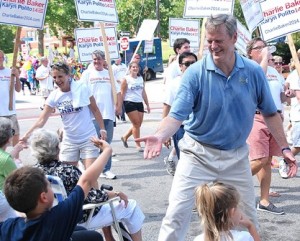 A young parade spectator gives a high five to Charlie Baker, a Republican candidate for governor.