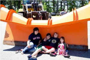 (l to r) Ashley Costello, Adam Costello, Connor Smith, Hailey Costello, and Annalee Theobald relaxe in the shade of a big plow after playing in the big trucks.