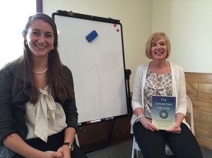 Holding the book she authored, Nancy Swanberg (r), founder of The Friendship Network for Children, sits in the training space at the agency’s new facility in Northborough, with Tiffany Kline, counselor and service coordinator. (Photo/Lori Berkey)
